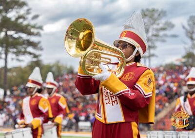 Person in crimson and gold band uniform playing instrument